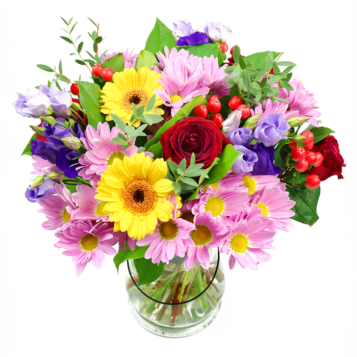 A tall, exuberant bouquet overflows from a clear glass vase, captured against a spotless white background that highlights the intricate play of colours and textures. At the centre, plush deep red roses unfold in layered spirals, their velvety petals giving the entire design a sense of romance and depth, like a classic love note delivered to a home tucked between Brompton and neighbouring Chelsea. Radiant yellow gerbera daisies with dark, warm-toned centres sit proudly among the roses, their open faces and strong petals bringing a burst of sunshine that instantly brightens the mood. Encircling these focal flowers, soft pink chrysanthemums cluster densely, each bloom with fine, feather-like petals and a neat yellow centre, creating a cushion of gentle colour that softens and enlarges the composition. Woven delicately throughout the arrangement are purple and lavender lisianthus, their slender stems and bell-shaped blossoms lending a refined grace and a slightly cool, contemporary contrast, reminiscent of the calm, elegant terraces along Queen's Gate. Nestled between the petals, bright red hypericum berries gleam like small, polished beads, adding a pleasantly tactile texture and glimpses of vivid colour. A varied selection of greenery anchors the bouquet, with large, darker leaves providing structure while lighter, more delicate sprigs add airiness and movement, as if the bouquet might rustle softly with each passing breeze. Through the transparent sides of the vase, the cleanly trimmed stems can be seen resting in fresh water, emphasising the professional finish and freshness of the arrangement. This mixed-colour design feels perfectly suited to birthdays, thank-you gestures, or welcoming a new neighbour in Brompton, offering a joyful, uplifting presence that would sit beautifully on a dining table or hallway console.